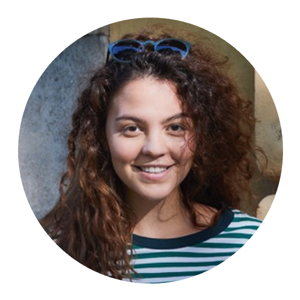 Portrait von Aylin, eine junge Frau mit braunen Locken, die freundlich in die Kamera lächelt.